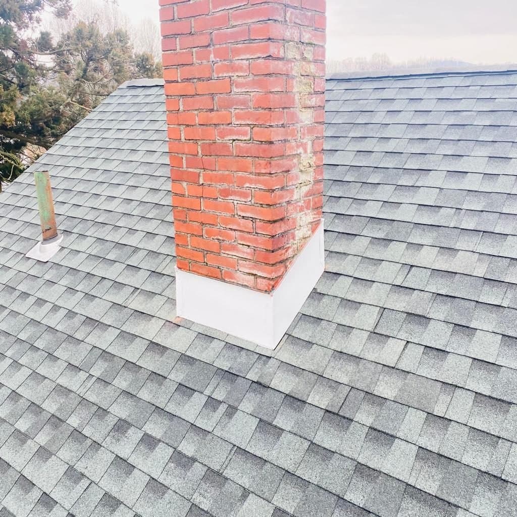 Brick chimney with fresh flashing on a shingle roof